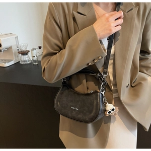 Detail der schwarzen Satteltasche mit Markenschriftzug und süßem Plüsch-Anhänger