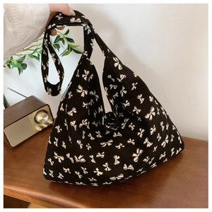 Close-up of black corduroy tote bag with white bow patterns and soft texture