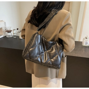 Rear view of a model wearing the black quilted leather crossbody bag in a cozy cafe setting