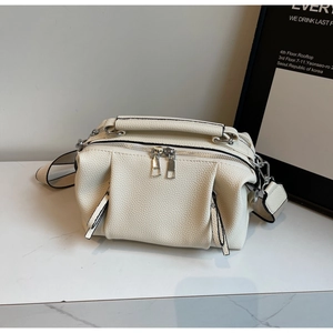Macro shot of off-white leather texture and silver dual zippers on stylish pillow bag