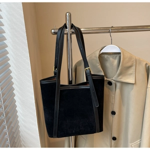 Detail of black suede tote bag with leather trim and adjustable metal buckle