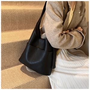 Detailed view of black leather hobo bucket bag styled with a grey blazer and skirt