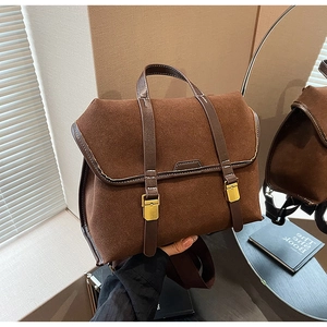 Detail einer braunen Vintage-Wildledertasche mit Zierriemen aus Leder und Goldschnallen