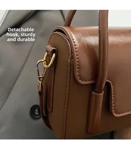 Detail of brown leather handbag featuring gold detachable buckle and sturdy hardware