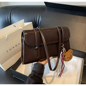Detail view of dark brown oil wax leather shoulder bag with cute bear charm and gift box