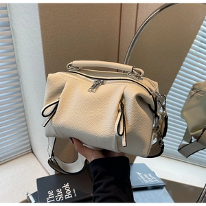 Close-up of beige lychee grain leather handbag with silver hardware and shoulder strap