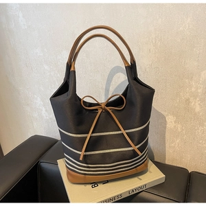 Detailed close-up of striped canvas tote bag with brown leather handles on business book