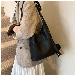 Detail of minimalist black leather tote bag with side pocket and adjustable shoulder strap