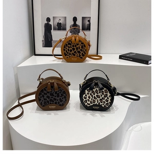 Three circular leopard print bags in yellow, brown, and black on a display stand