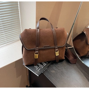 Nahaufnahme der braunen Wildledertasche mit goldenen Schnallen und breitem Riemen