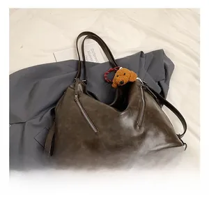 Dettaglio della borsa tote marrone vintage con zip in metallo e ciondolo orsetto