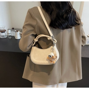 Detail der beigen Wildleder-Satteltasche mit Knotengriff und braunem Plüsch-Anhänger