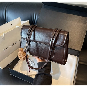 Close-up of vintage brown oil wax leather shoulder bag in a gift box with accessories