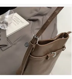 Detail of vintage brown leather bucket bag showing silver metal buckle and strap