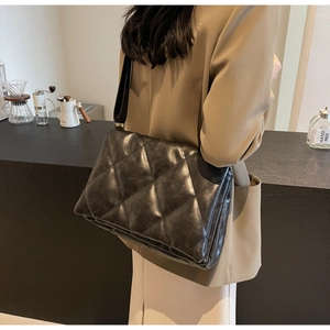 Macro detail of black quilted leather crossbody bag with vintage diamond stitching