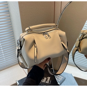 Detail of cream pleated crossbody bag with wide strap and lychee grain leather texture