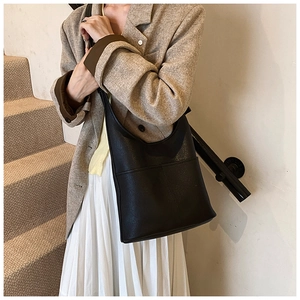 Modern black leather bucket shoulder bag styled with a professional khaki office blazer outfit