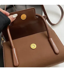 Detailed macro of the brown square bag showing premium gold magnetic clasp and inner lining