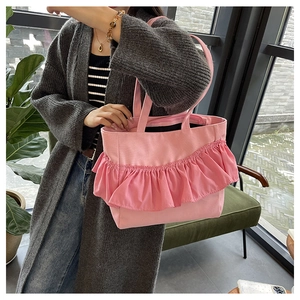 Detailed view of pink canvas tote bag with ruffled pleats and long shoulder straps