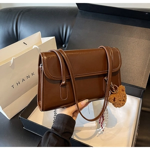 Detailed macro view of brown faux leather shoulder bag with plush bear accessory