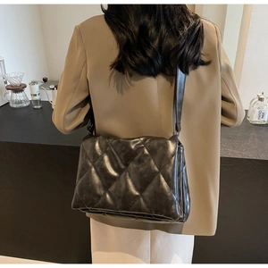 Close-up of a black quilted crossbody bag worn with a stylish blazer for commute