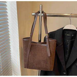 Close-up of deep brown suede tote bag with leather handles on a metal hanger
