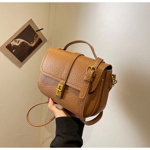 Detail of vintage brown lychee grain leather crossbody bag with metal twist lock