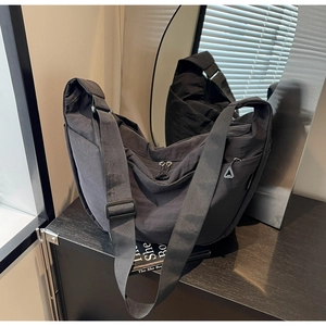 Detailed view of the black crossbody bag showing nylon texture and adjustable strap
