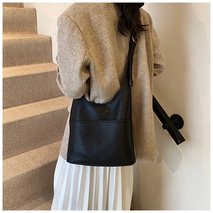 Detail of black leather shoulder bag showing the textured surface and side pocket design