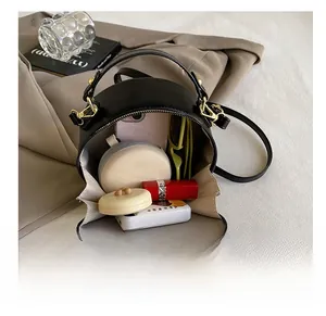 Detail view of the round black bag's spacious interior with makeup and phone storage
