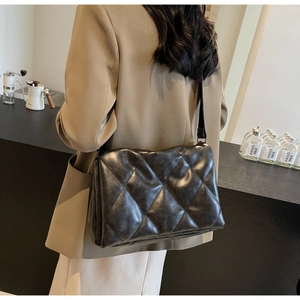 Detailed side view of black quilted faux leather crossbody bag worn by a model