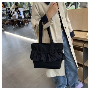 Close-up of black canvas tote bag featuring stylish ruffled pleated details and cotton texture