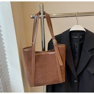 Detail view of dark brown suede and leather patchwork tote bag hanging on a metal rack