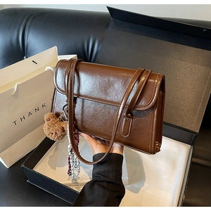 Close-up of vintage brown gloss leather shoulder bag with bear charm and ribbon decoration