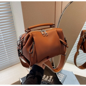 Close-up of brown litchi grain leather pillow bag with dual zippers and wide shoulder strap