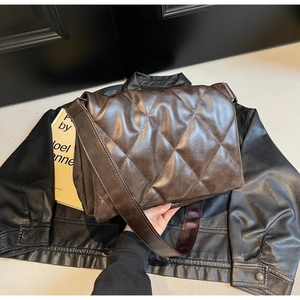 Detail of dark brown quilted crossbody bag with rhombic pattern on leather texture