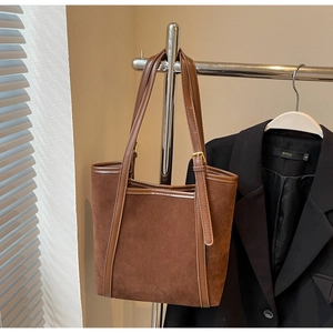 Detail of dark brown tote bag featuring mixed suede and smooth leather texture with gold hardware