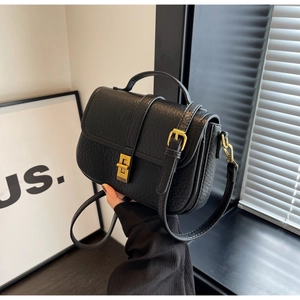 Close-up of black textured leather mini bag featuring gold twist lock and handle