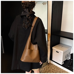 Detail of vintage brown leather hobo bag with front pockets shown on a model back