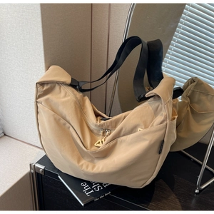 Detailed close-up of khaki nylon crescent bag featuring black strap and metal zipper