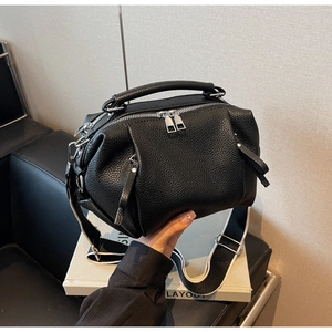 Detail of black lychee grain leather handbag with silver double zippers and wide strap