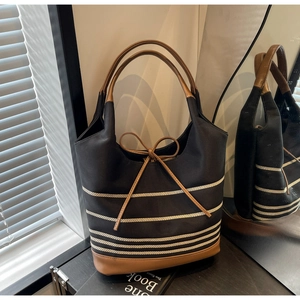 Close-up of canvas tote bag with brown leather bow and striped pattern in modern interior