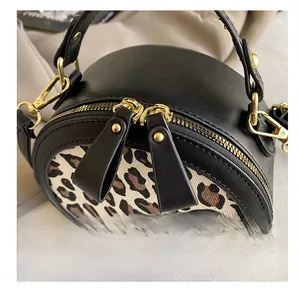Detail showing smooth gold-tone zippers and leopard print stitching on round crossbody bag