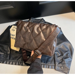 Detail of dark brown quilted crossbody bag with wide strap and silver metal buckle