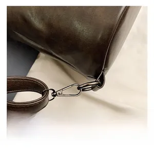 Dettaglio macro del gancio metallico su uno zaino vintage in pelle marrone
