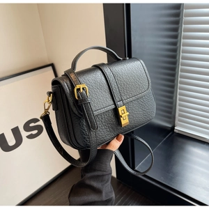Macro detail of black pebble leather texture and gold twist lock on women bag