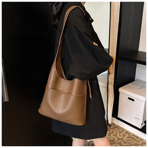 Macro shot of brown leather tote bag with grainy texture and decorative stitching details