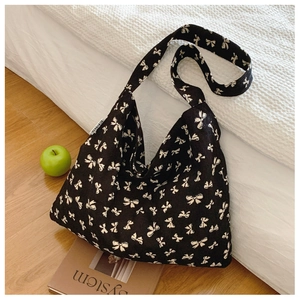 Detail view of black canvas tote bag featuring white bow patterns and soft woven texture