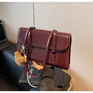 Detail of vintage burgundy shoulder bag with glossy finish and cute plush bear charm
