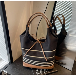 Detailed view of the striped canvas tote bag with brown faux leather straps and bow